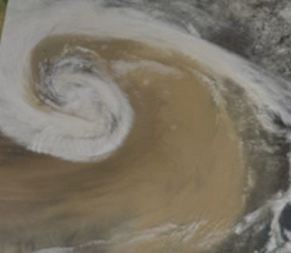 A giant brown cloud covers a large bit of the earth.  Seen from outer-space.